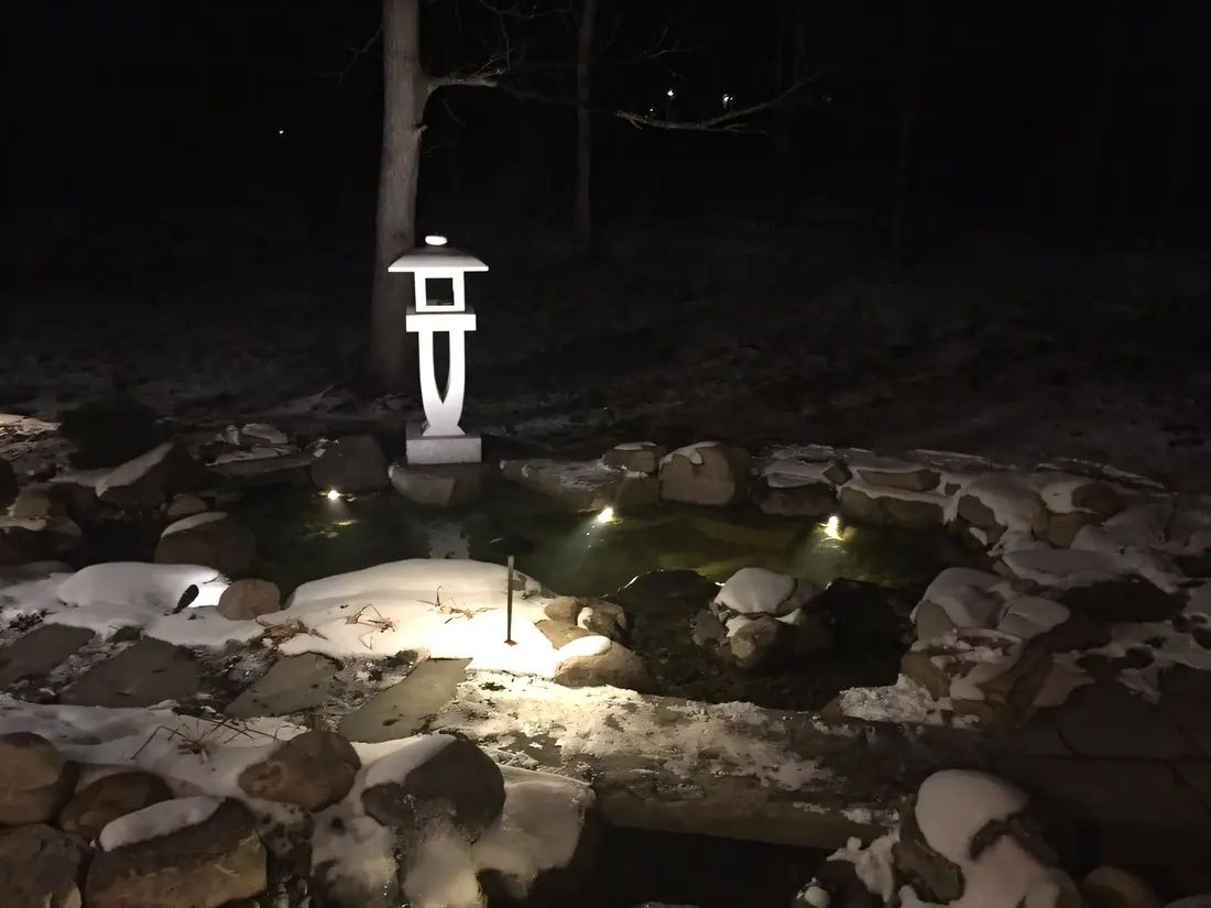 Amayana lantern lit beside a garden pond at night